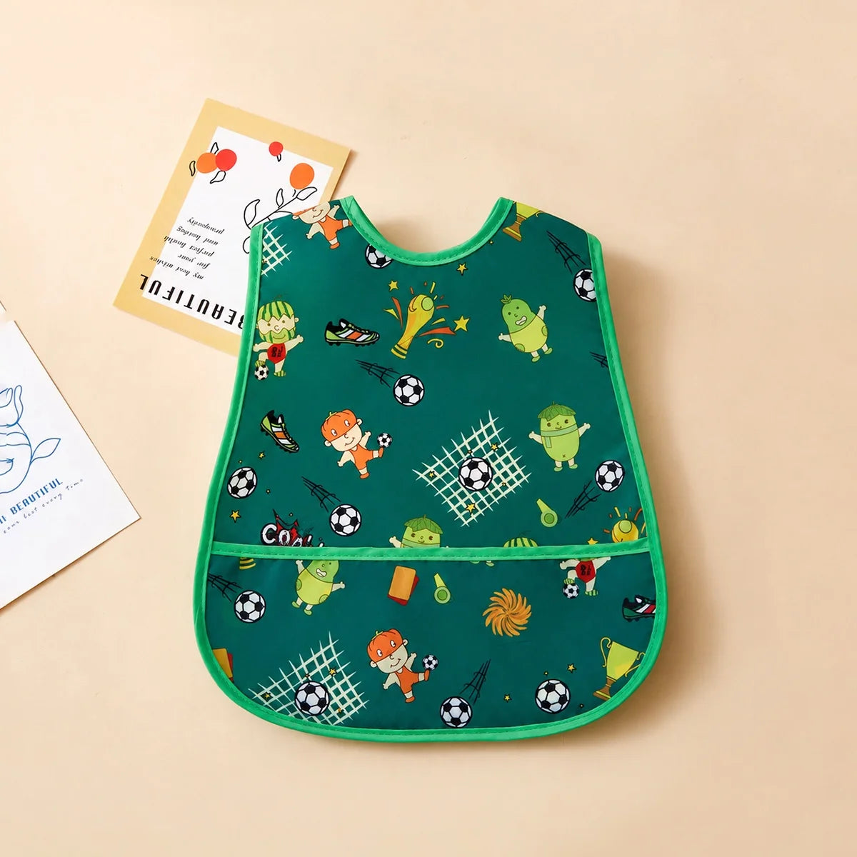 A baby meal cover with no cuffs and a cartoon print design in multiple colors, suitable for wearing while eating